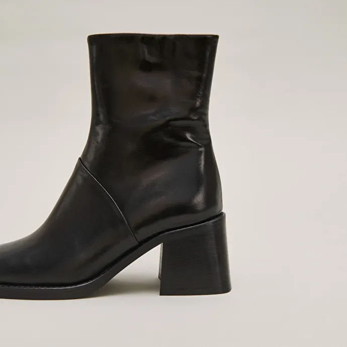 Square-toe boots with exposed seams in black leather